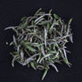 Macro photograph of Silver Needle White Tea buds with silver-white fuzz